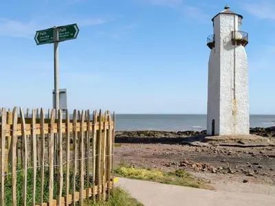 a lighthouse on the beach next to a fence at Sea View 59 - Uk45586 in Mainsriddle