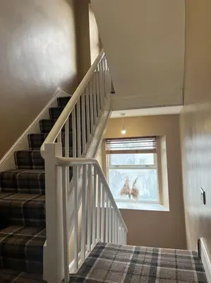 a white staircase in a house with a window at Tynwald Apartments in Douglas