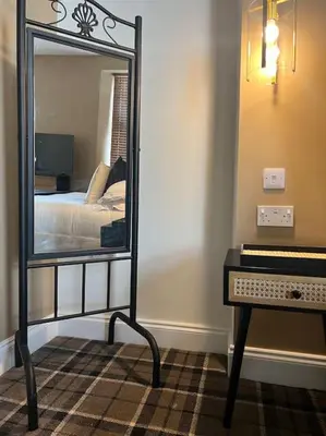 a mirror in a room with a bed and a piano at Tynwald Apartments in Douglas