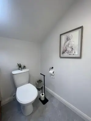 a bathroom with a toilet and a picture on the wall at Tynwald Apartments in Douglas