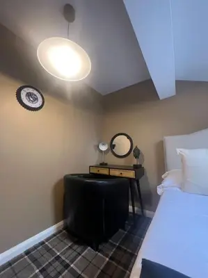 a bedroom with a bed and a table with a mirror at Tynwald Apartments in Douglas