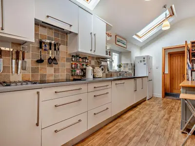 a kitchen with white cabinets and a wooden floor at 3 Bed in Keswick oc-94346 in Threlkeld