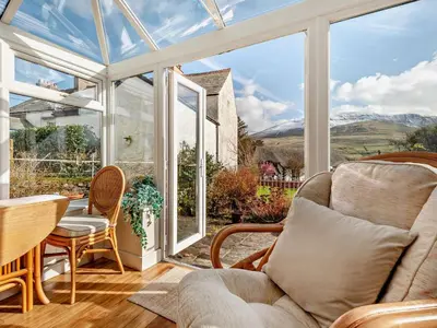 a conservatory with a couch and a table and chairs at 3 Bed in Keswick oc-94346 in Threlkeld