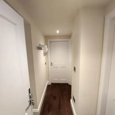 a hallway with a white door and wooden floors at Kirkcudbright Holiday Apartments - Apartment A in Kirkcudbright