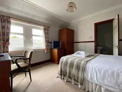 a bedroom with a bed and a desk and a chair at Kings Arms Hotel in Lockerbie
