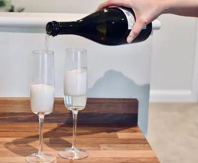 a person pouring a bottle of wine into two glasses at *Penthouse Luxury Apartment 2min to City in Carlisle