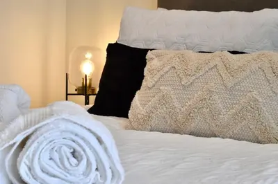 a bed with a white blanket and pillows on it at *Penthouse Luxury Apartment 2min to City in Carlisle
