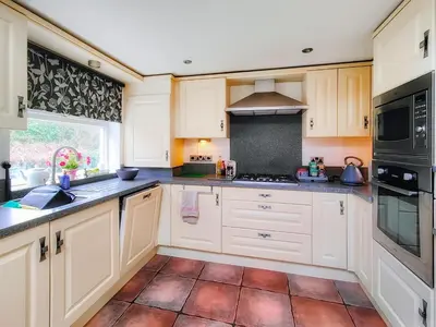 a kitchen with white cabinets and a tile floor at Little Hills in Keswick