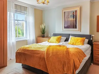a bedroom with a bed with an orange blanket on it at Little Hills in Keswick