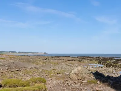 a rocky beach with the ocean in the background at Sandy Paws - Uk45511 in Mainsriddle