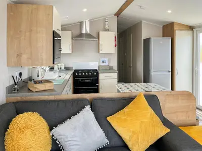 a living room with a couch and a kitchen at Sandy Paws - Uk45511 in Mainsriddle