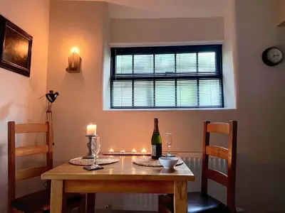 a dining room table with a bottle of wine and a window at 1 Bed in Ullswater 94064 in Watermillock