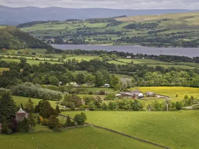 an aerial view of a green field with a lake at 1 Bed in Ullswater 94064 in Watermillock