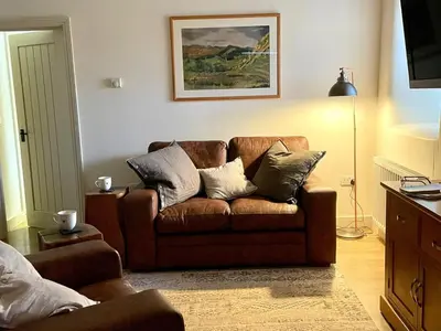 a living room with a brown couch with pillows at 1 Bed in Watermillock 94065 in Watermillock