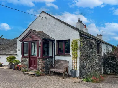 a house with a bench in front of it at Bassenthwaite Farm Cottage, on a working farm in a tranquil setting in Bassenthwaite