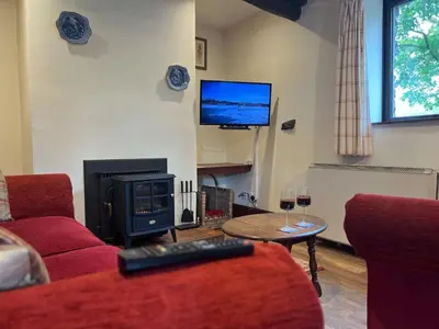 a living room with a couch and a fire place at Bassenthwaite Farm Cottage, on a working farm in a tranquil setting in Bassenthwaite