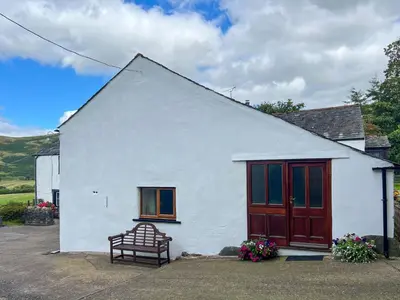 a white house with a bench in front of it at Fell View Bassenthwaite, rural location on a working farm in the fells in Bassenthwaite