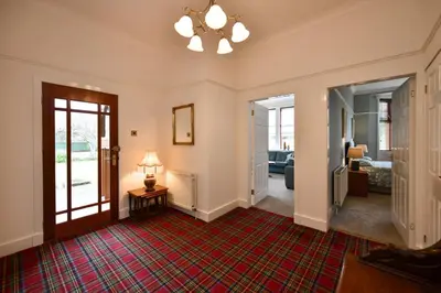 a hallway with a living room with a table and a lamp at Dunvegan Apartment Troon in Troon