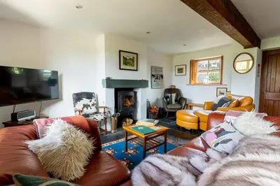 a living room with leather couches and a fireplace at HIGH TREES BYRE - Two bed Cottage with Log Burner & Incredible Views in Workington