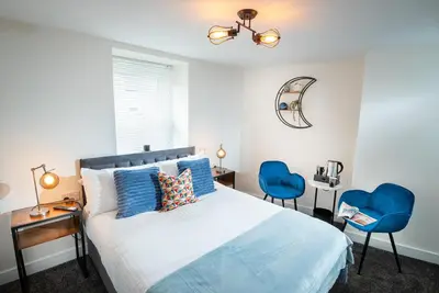 a bedroom with a bed and two blue chairs at Kings Arms Suites - Deluxe Room - En-Suite - Self Check In in Whitehaven