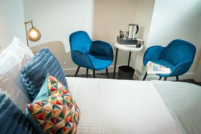 two blue chairs and a bed in a room at Kings Arms Suites - Deluxe Room - En-Suite - Self Check In in Whitehaven