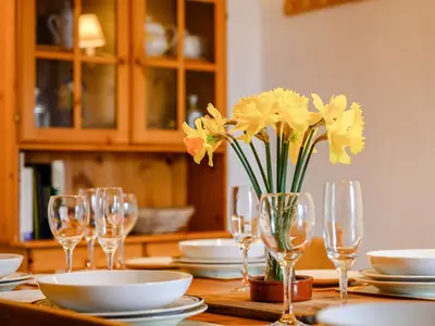 a table with glasses and a vase of yellow flowers at 3 Bed in Watermillock SZ318 in Watermillock