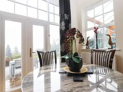 a dining room with a glass table with a vase on it at 5 Ladstock Hall in Keswick