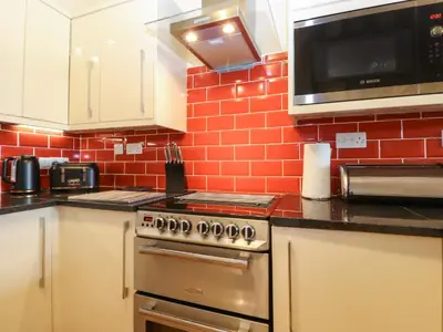 a kitchen with a stove and a microwave at 5 Ladstock Hall in Keswick