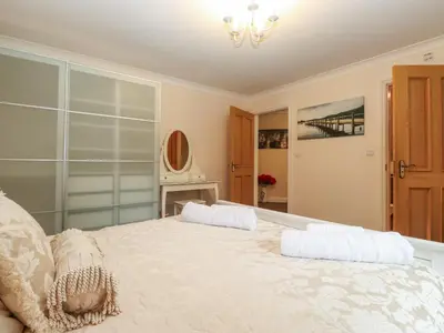 a bedroom with a large white bed with a chandelier at 5 Ladstock Hall in Keswick