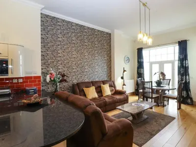 a living room with a couch and a brick wall at 5 Ladstock Hall in Keswick