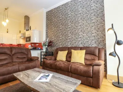 a living room with two brown couches and a brick wall at 5 Ladstock Hall in Keswick