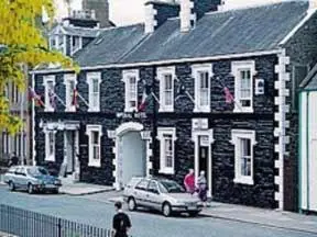 a black brick building with cars parked in front of it at The Imperial Hotel in Castle Douglas