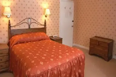 a bedroom with a bed with an orange comforter at The Imperial Hotel in Castle Douglas