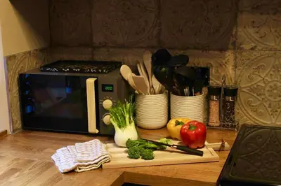 a counter with a cutting board with vegetables and a microwave at Holmlea Cottage in Moffat
