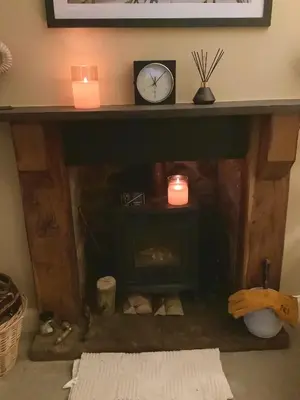 a fireplace with two candles and a clock on top at Holmlea Cottage in Moffat