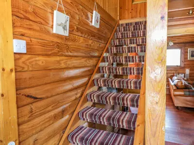 a staircase in a log cabin with wooden walls at Thistle Dubh 