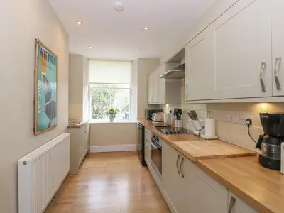 a kitchen with white cabinets and a wooden counter top at Baystones in Keswick