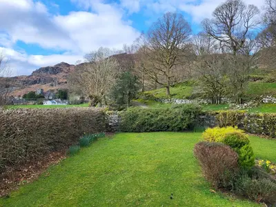 a garden with a stone wall and green grass at Beckfoot Chapel Stile - Ambleside in Chapel Stile