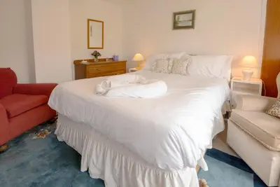 a bedroom with a large white bed and a red chair at Beckfoot Chapel Stile - Ambleside in Chapel Stile