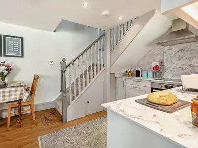 a kitchen with white walls and a staircase with a table at 1 Bed in Bassenthwaite 91211 in Bassenthwaite Lake