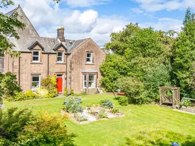 an exterior view of a large brick house with a garden at Mansefield Rooms in Lockerbie