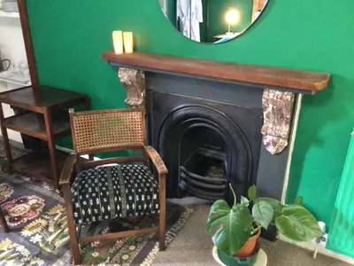 a room with a fireplace and a chair and a mirror at Mansefield Rooms in Lockerbie