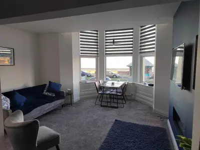 a living room with a couch and a table and windows at Antrim Holiday Apartment in Ramsey