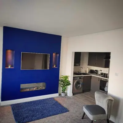 a living room with a blue wall and a chair at Antrim Holiday Apartment in Ramsey