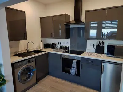 a kitchen with blue cabinets and a washer and dryer at Antrim Holiday Apartment in Ramsey