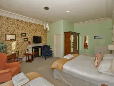 a bedroom with two beds and a couch and a fireplace at Clonyard House Hotel in Dalbeattie