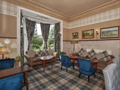 a living room with a couch and a table and chairs at Clonyard House Hotel in Dalbeattie