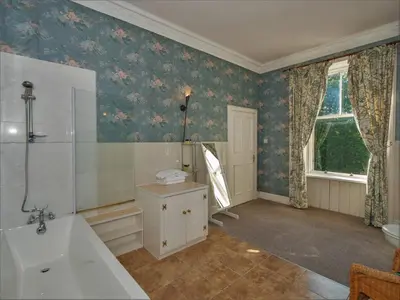 a bathroom with a bath tub and a sink at Clonyard House Hotel in Dalbeattie