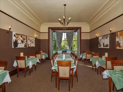 a dining room with green tables and chairs and a chandelier at Clonyard House Hotel in Dalbeattie