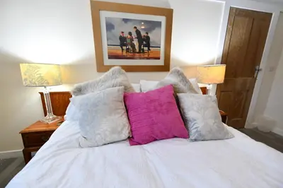 a bedroom with a white bed with colorful pillows at Ladyland Cottage in Maybole in Maybole